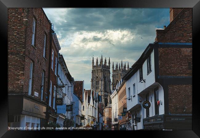 Quaint European street leading to a majestic Gothic cathedral under a dramatic sky at dusk, showcasing historical architecture and urban charm in York, North Yorkshire, England. Framed Print by Man And Life