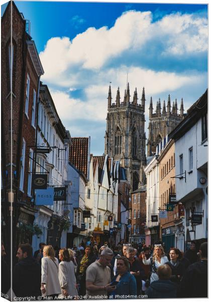 Bustling street scene with pedestrians in a historic city center, featuring old buildings and a prominent Gothic cathedral under a cloudy sky in York, North Yorkshire, England. Canvas Print by Man And Life