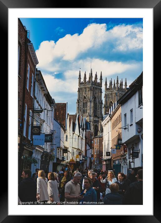 Bustling street scene with pedestrians in a historic city center, featuring old buildings and a prominent Gothic cathedral under a cloudy sky in York, North Yorkshire, England. Framed Mounted Print by Man And Life