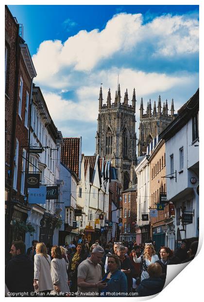Bustling street scene with pedestrians in a historic city center, featuring old buildings and a prominent Gothic cathedral under a cloudy sky in York, North Yorkshire, England. Print by Man And Life