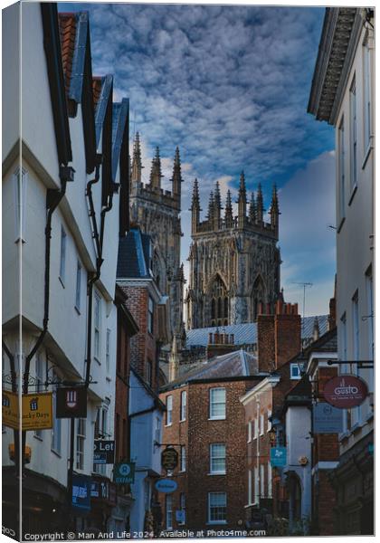 Historic European cityscape with Gothic cathedral towering over traditional buildings under a dramatic cloudy sky in York, North Yorkshire, England. Canvas Print by Man And Life