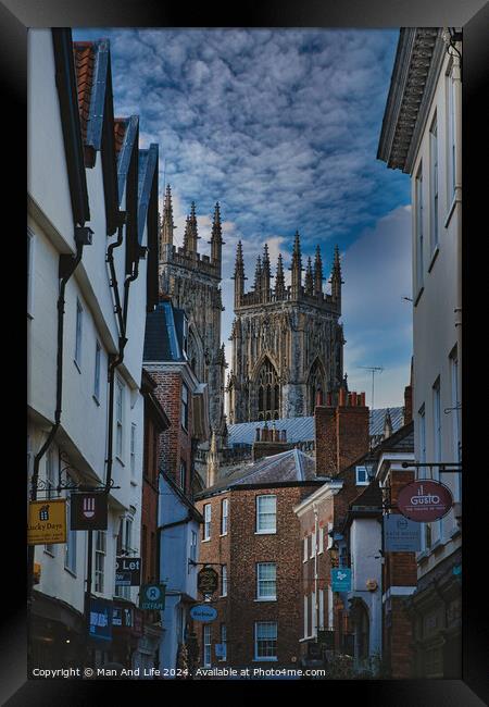 Historic European cityscape with Gothic cathedral towering over traditional buildings under a dramatic cloudy sky in York, North Yorkshire, England. Framed Print by Man And Life
