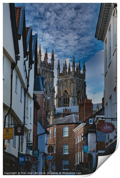 Historic European cityscape with Gothic cathedral towering over traditional buildings under a dramatic cloudy sky in York, North Yorkshire, England. Print by Man And Life