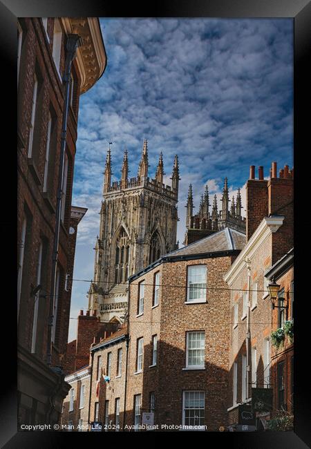 Quaint cobbled street leading to a majestic Gothic cathedral under a blue sky with wispy clouds, showcasing historical architecture and urban charm in York, North Yorkshire, England. Framed Print by Man And Life