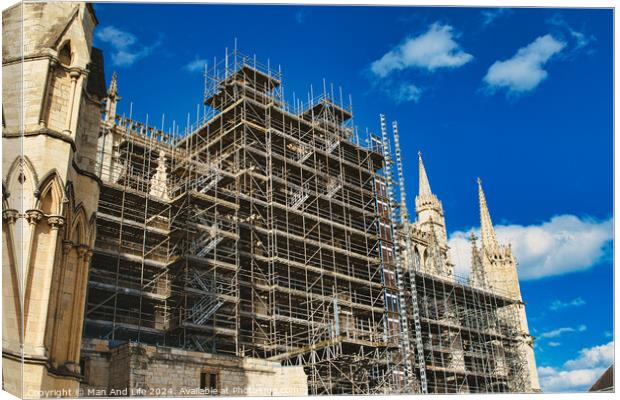 Historic cathedral undergoing renovation, with intricate scaffolding against a bright blue sky with clouds. Architectural preservation concept in York, North Yorkshire, England. Canvas Print by Man And Life