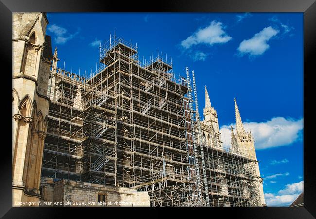 Historic cathedral undergoing renovation, with intricate scaffolding against a bright blue sky with clouds. Architectural preservation concept in York, North Yorkshire, England. Framed Print by Man And Life