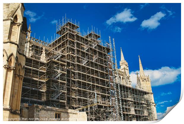 Historic cathedral undergoing renovation, with intricate scaffolding against a bright blue sky with clouds. Architectural preservation concept in York, North Yorkshire, England. Print by Man And Life