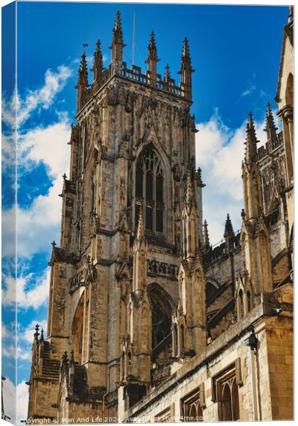 Gothic cathedral tower against a blue sky with clouds, showcasing intricate architectural details and flying buttresses in York, North Yorkshire, England. Canvas Print by Man And Life