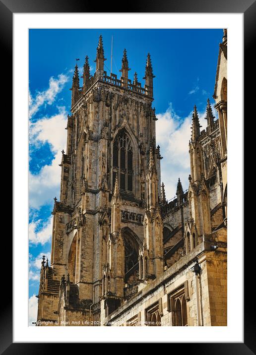 Gothic cathedral tower against a blue sky with clouds, showcasing intricate architectural details and flying buttresses in York, North Yorkshire, England. Framed Mounted Print by Man And Life