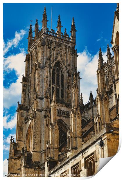 Gothic cathedral tower against a blue sky with clouds, showcasing intricate architectural details and flying buttresses in York, North Yorkshire, England. Print by Man And Life