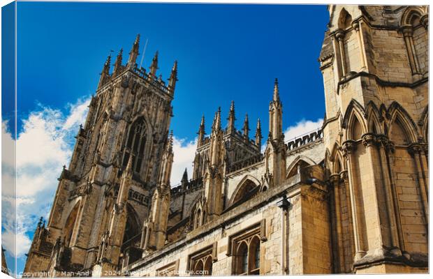 Majestic Gothic cathedral against a blue sky with clouds, showcasing intricate architecture and historical religious significance in York, North Yorkshire, England. Canvas Print by Man And Life