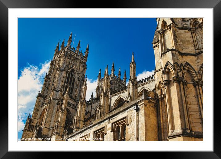 Majestic Gothic cathedral against a blue sky with clouds, showcasing intricate architecture and historical religious significance in York, North Yorkshire, England. Framed Mounted Print by Man And Life