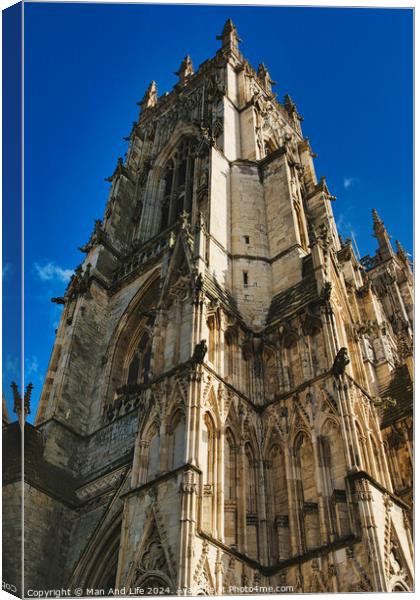 Gothic cathedral facade with intricate architecture against a clear blue sky, showcasing historical religious building's exterior details in York, North Yorkshire, England. Canvas Print by Man And Life