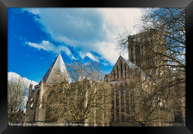 Historic medieval cathedral with Gothic architecture, featuring pointed arches and robust stone walls, set against a vibrant blue sky with fluffy clouds in York, North Yorkshire, England. Framed Print by Man And Life