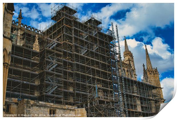 Gothic cathedral undergoing restoration, with extensive scaffolding against a dramatic cloudy sky in York, North Yorkshire, England. Print by Man And Life