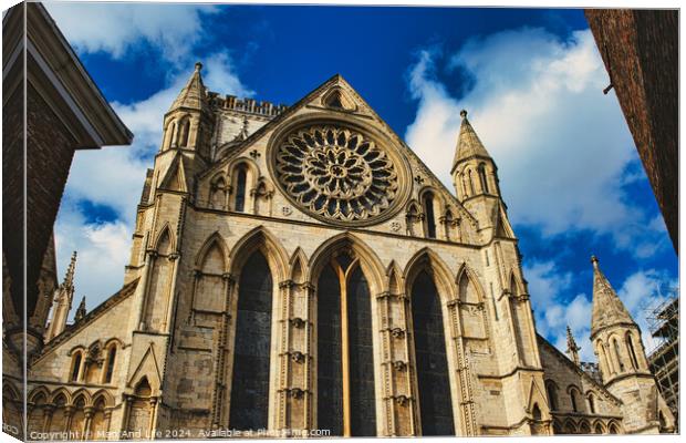 Gothic cathedral facade with rose window and spires against a blue sky with clouds, framed by trees in York, North Yorkshire, England. Canvas Print by Man And Life