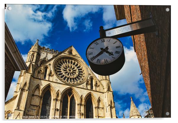 Vintage street clock hanging with a gothic cathedral facade in the background, showcasing intricate architecture and a clear blue sky in York, North Yorkshire, England. Acrylic by Man And Life