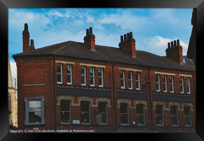 Traditional red brick building with multiple chimneys against a blue sky with light clouds, showcasing classic urban architecture in York, North Yorkshire, England. Framed Print by Man And Life