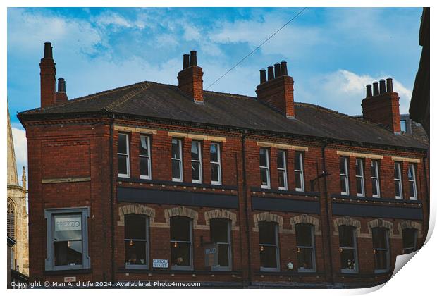 Traditional red brick building with multiple chimneys against a blue sky with light clouds, showcasing classic urban architecture in York, North Yorkshire, England. Print by Man And Life