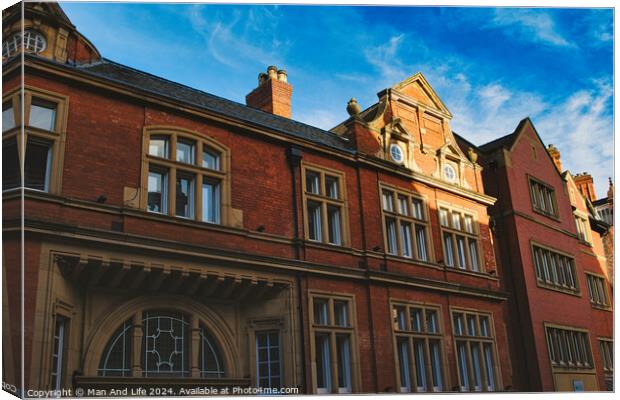 Traditional red brick building with ornate windows under a clear blue sky, showcasing classic architectural details and warm sunlight casting shadows in York, North Yorkshire, England. Canvas Print by Man And Life