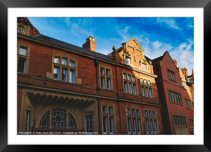 Traditional red brick building with ornate windows under a clear blue sky, showcasing classic architectural details and warm sunlight casting shadows in York, North Yorkshire, England. Framed Mounted Print by Man And Life