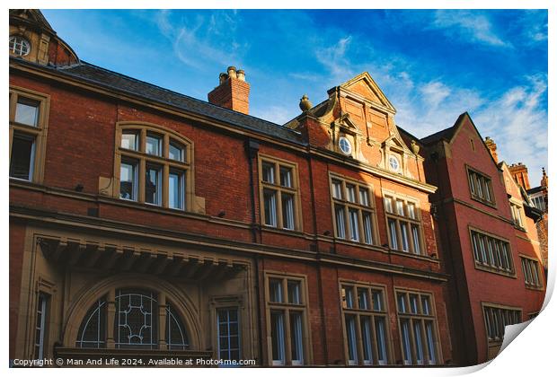 Traditional red brick building with ornate windows under a clear blue sky, showcasing classic architectural details and warm sunlight casting shadows in York, North Yorkshire, England. Print by Man And Life