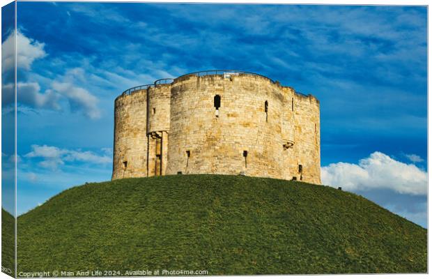 Medieval stone tower atop a lush green hill against a vibrant blue sky with fluffy clouds, symbolizing historical fortification and ancient architecture in York, North Yorkshire, England. Canvas Print by Man And Life