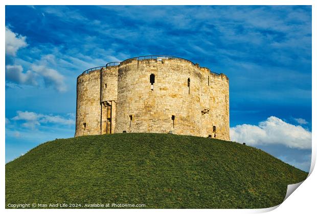 Medieval stone tower atop a lush green hill against a vibrant blue sky with fluffy clouds, symbolizing historical fortification and ancient architecture in York, North Yorkshire, England. Print by Man And Life