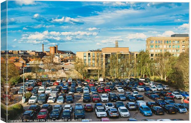 Urban parking lot filled with cars on a sunny day, with city buildings in the background and a clear blue sky overhead in York, North Yorkshire, England. Canvas Print by Man And Life