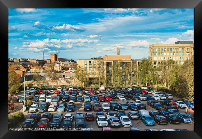 Urban parking lot filled with cars on a sunny day, with city buildings in the background and a clear blue sky overhead in York, North Yorkshire, England. Framed Print by Man And Life