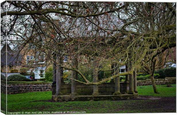 Tranquil park scene with bare-branched trees in early spring, showcasing a rustic stone bench beneath, on a carpet of green grass, with residential buildings in the background in Harrogate, North Yorkshire. Canvas Print by Man And Life