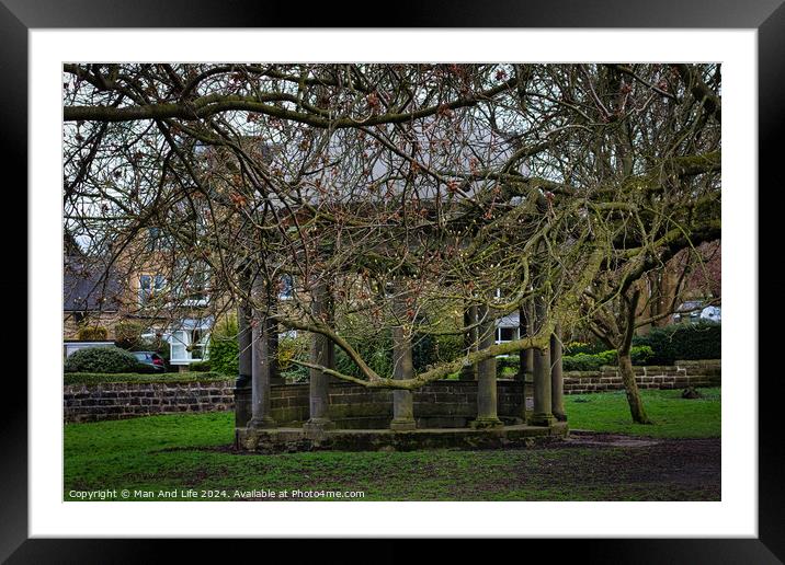 Tranquil park scene with bare-branched trees in early spring, showcasing a rustic stone bench beneath, on a carpet of green grass, with residential buildings in the background in Harrogate, North Yorkshire. Framed Mounted Print by Man And Life