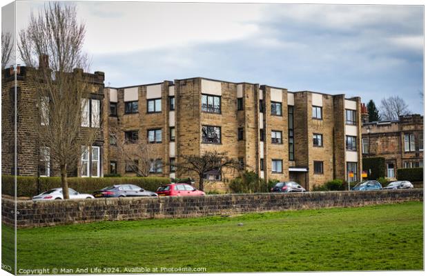 Modern residential apartment buildings with parked cars in front, behind a stone wall with a lush green lawn in the foreground. Urban living concept in Harrogate, North Yorkshire. Canvas Print by Man And Life