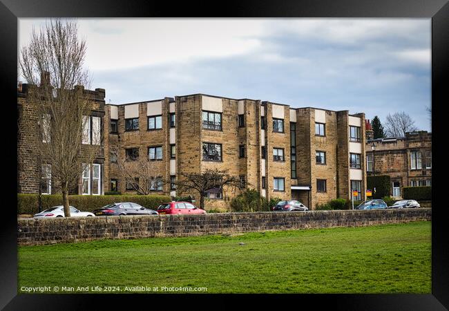 Modern residential apartment buildings with parked cars in front, behind a stone wall with a lush green lawn in the foreground. Urban living concept in Harrogate, North Yorkshire. Framed Print by Man And Life