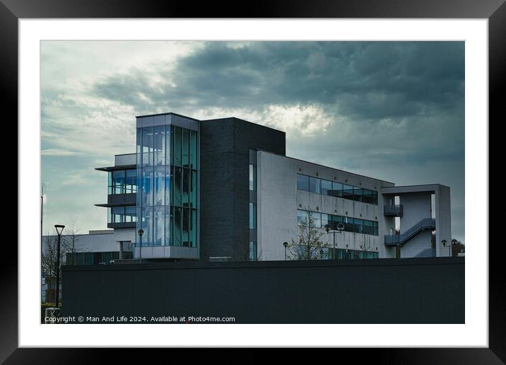 Modern office building against a dramatic cloudy sky, showcasing contemporary architecture with a mix of glass and concrete elements. Framed Mounted Print by Man And Life