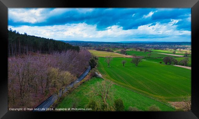 Aerial view of a vibrant rural landscape with a road running alongside a forest, contrasting green fields and a dramatic cloudy sky. Framed Print by Man And Life