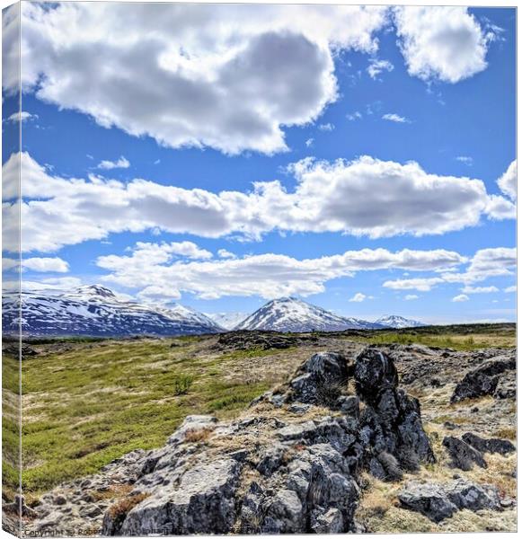 A rocky landscape with clouds and snowy mountains Canvas Print by Robert Galvin-Oliphant