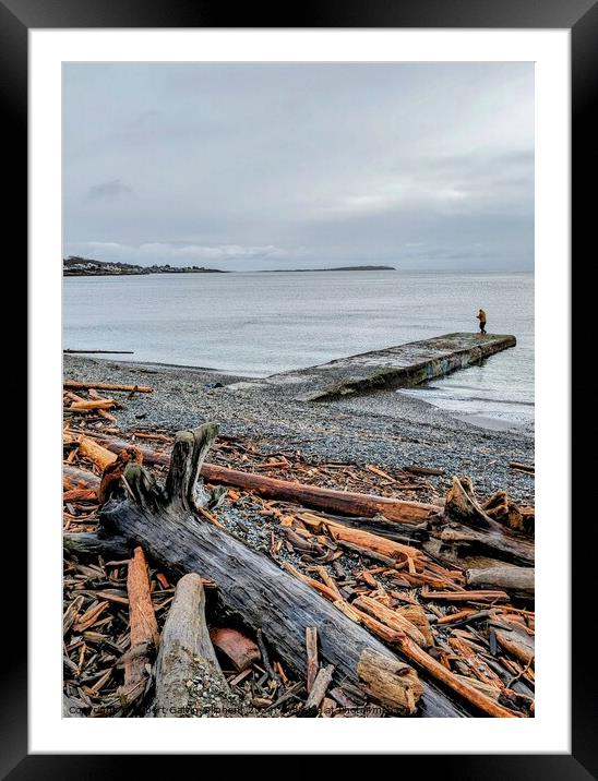 Fisherman on a pier at a log covered beach Framed Mounted Print by Robert Galvin-Oliphant