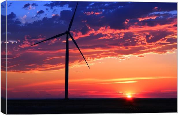 A silhouette of a wind turbine against a vibrant sunset backdrop Canvas Print by Michael Piepgras