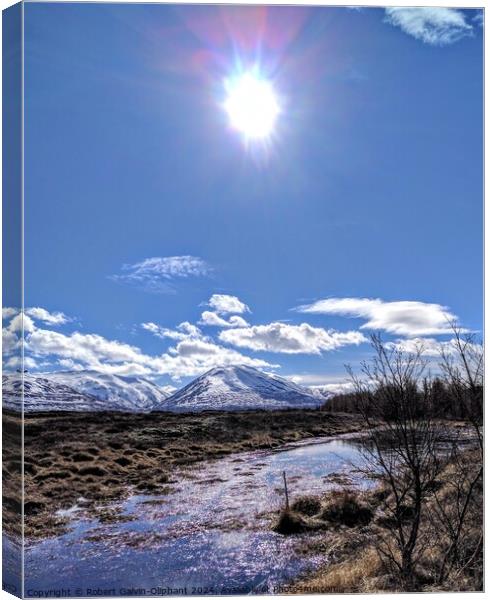 Sun shining on an icy pond and snowy mountains  Canvas Print by Robert Galvin-Oliphant