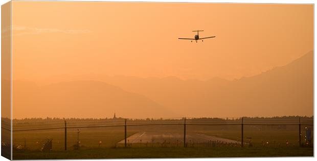 Light airplane landing at sunset Canvas Print by Ian Middleton
