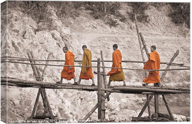 Buddhist monks across a bamboo bridge Canvas Print by stefano baldini