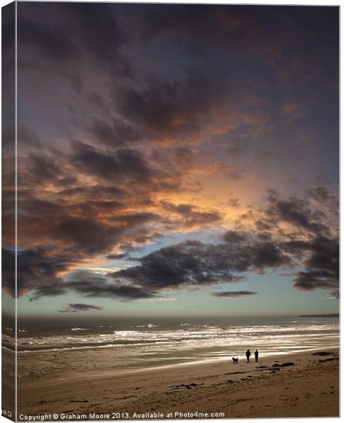 Couple walking on beach at sunset Canvas Print by Graham Moore