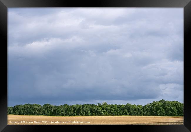 Dramatic rainclouds over rural field Framed Print by Liam Grant