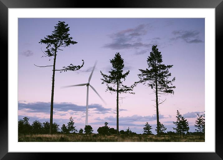 Wind turbine framed between three trees at dusk tw Framed Mounted Print by Liam Grant