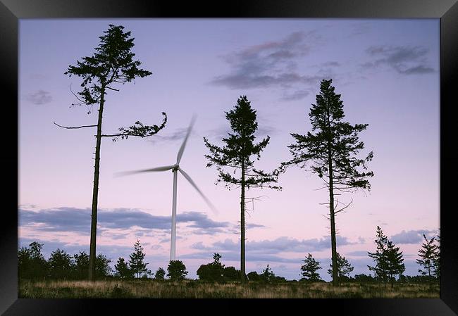 Wind turbine framed between three trees at dusk tw Framed Print by Liam Grant