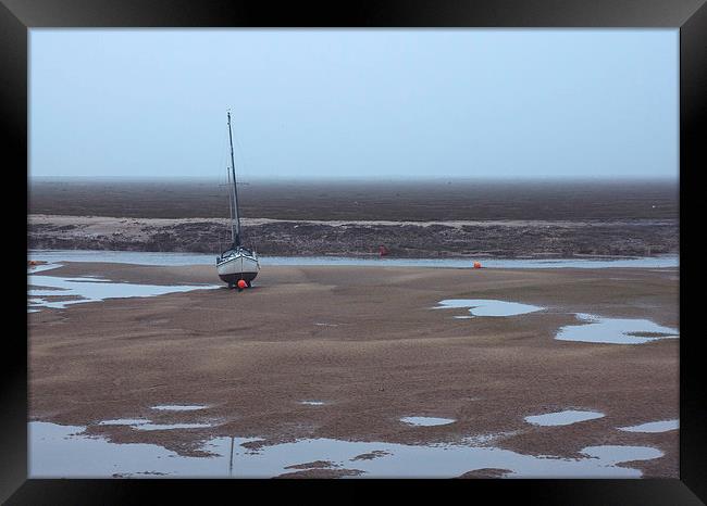 Boat at low tide on a foggy evening. Wells-next-th Framed Print by Liam Grant
