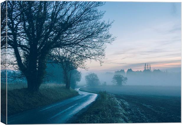 Evening sky over rural road leading into fog. Canvas Print by Liam Grant