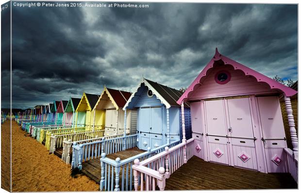 Row of colourful beach shelters.  Canvas Print by Peter Jones