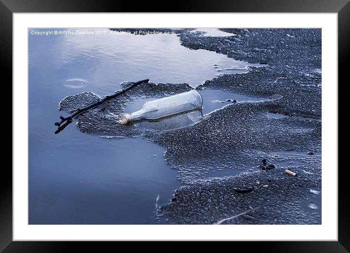 glass bottle garbage on melting ice on lake  Framed Mounted Print by Arletta Cwalina